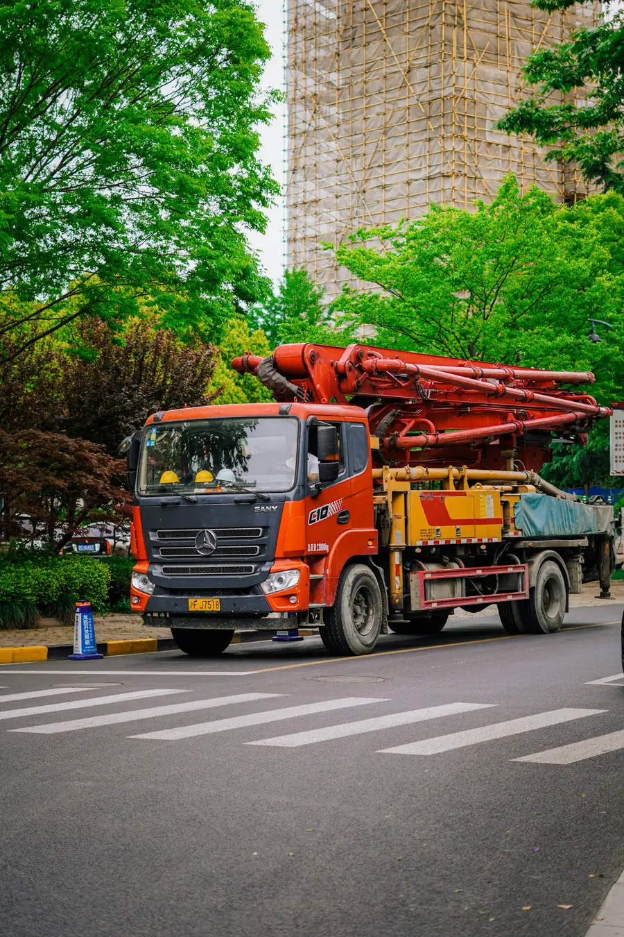 Orange concrete pump truck with boom on a city street